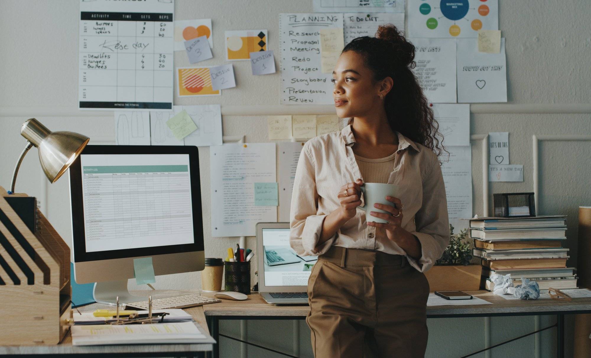 Shot of an attractive young businesswoman standing and looking contemplative while holding a cup of coffee in her home office Shot of an attractive young businesswoman standing and looking contemplative while holding a cup of coffee in her home office
