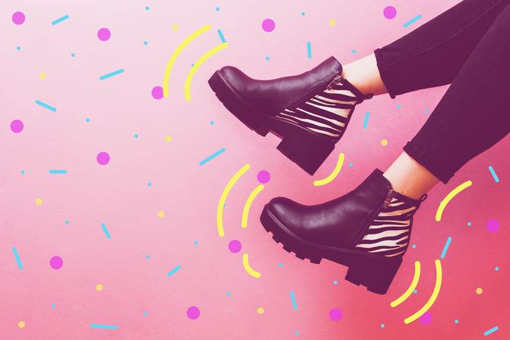 two women’s legs dangle in fashionable boots. two women's legs dangle in fashionable boots.