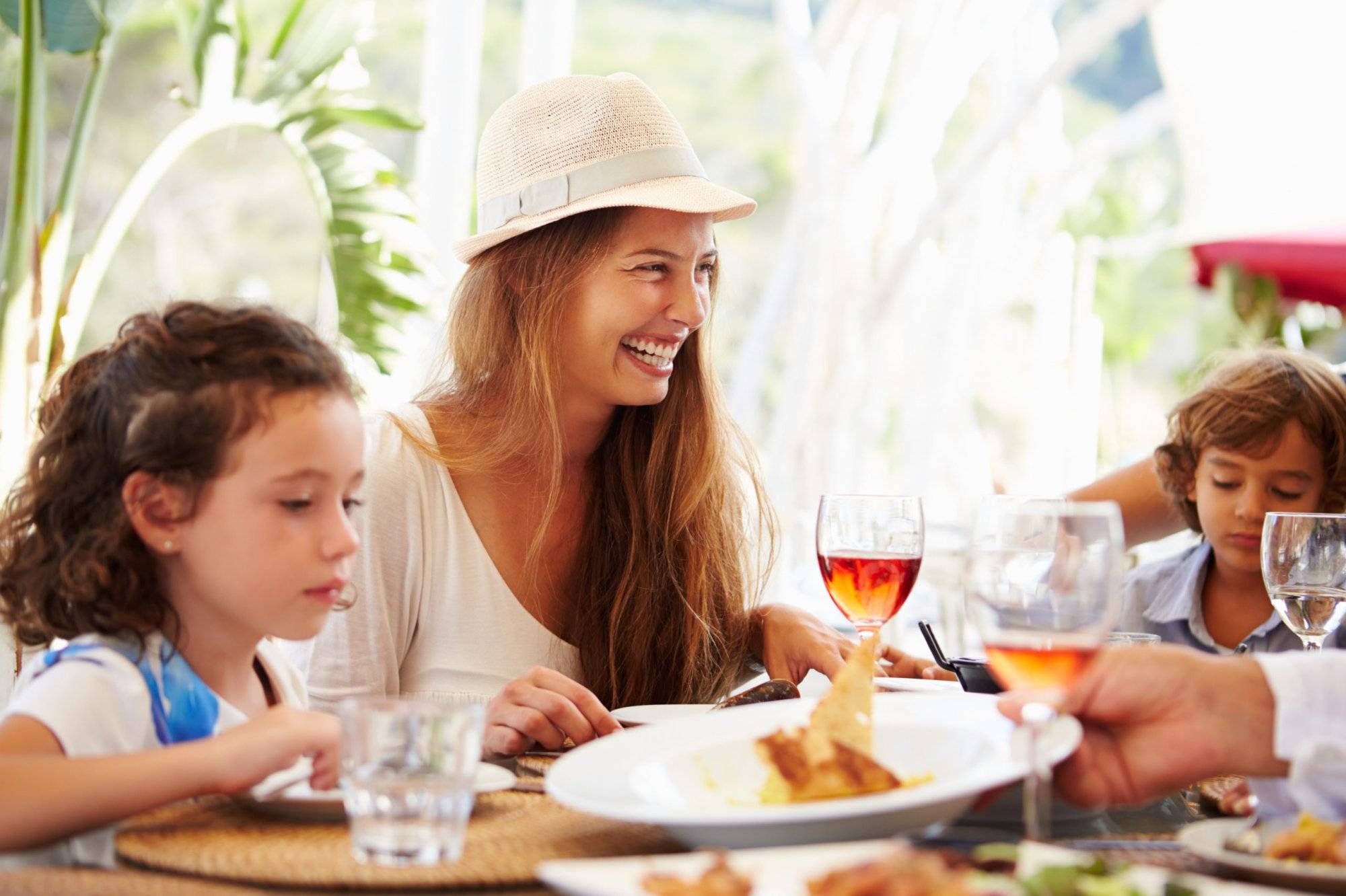 Mother With Children Enjoying Meal In Restaurant Mother With Children Enjoying Meal In Restaurant