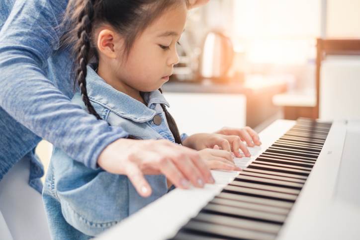 Asian young pianist teacher teaching girl kid student to play piano, music education concept Asian young pianist teacher teaching girl kid student to play piano, music education concept