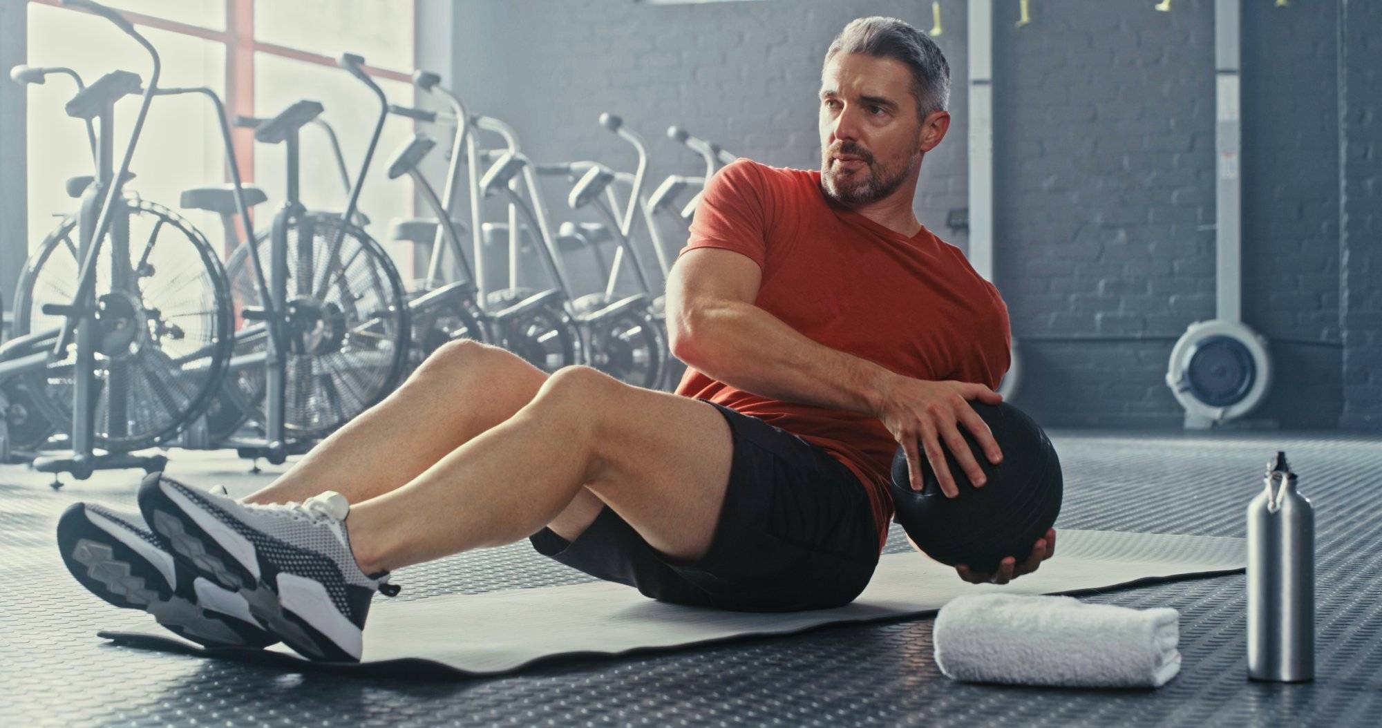 Shot of a handsome mature man using a medicine ball during his workout in the gym Shot of a handsome mature man using a medicine ball during his workout in the gym