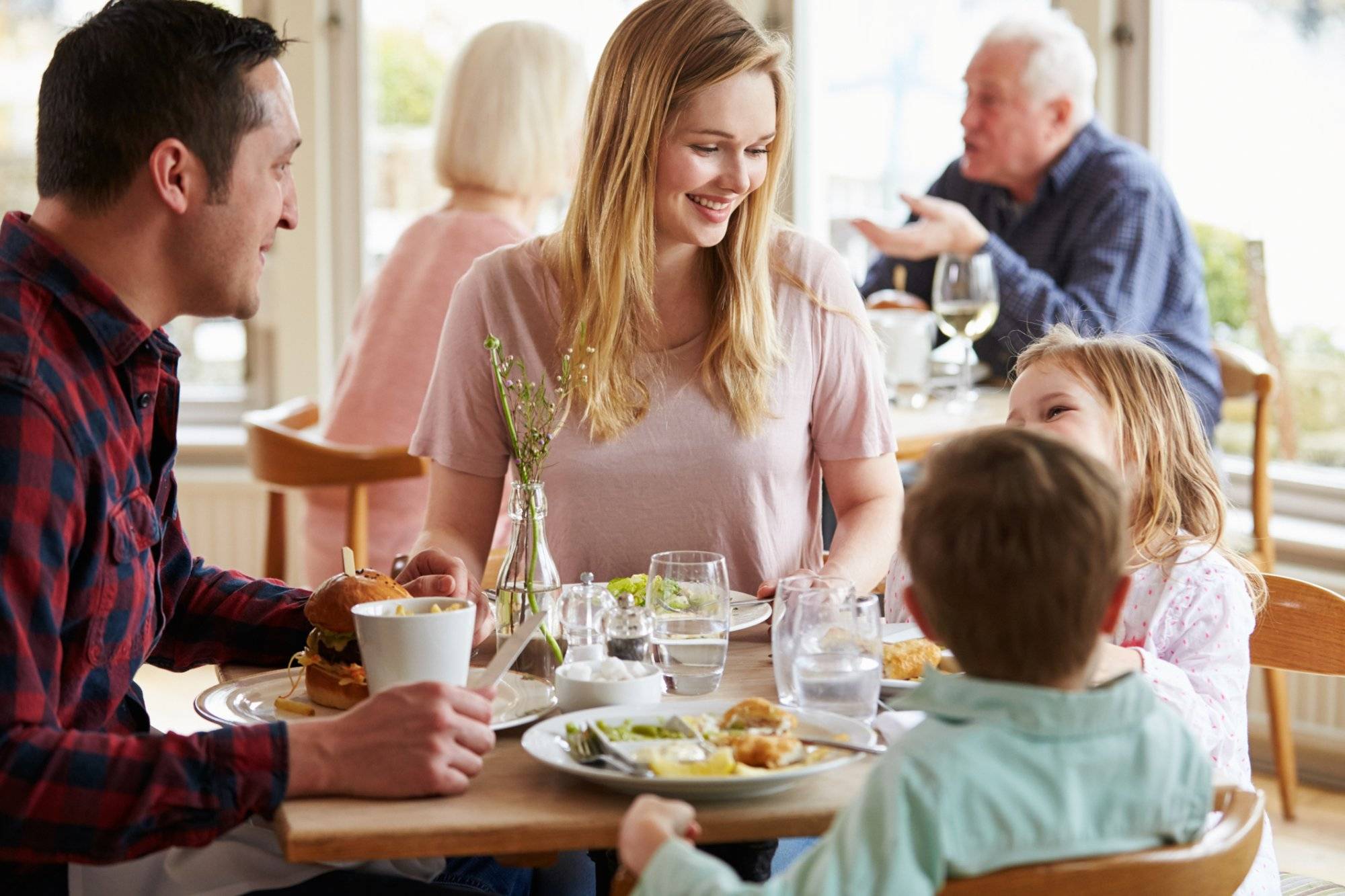 Family Enjoying Meal In Restaurant Together Family Enjoying Meal In Restaurant Together